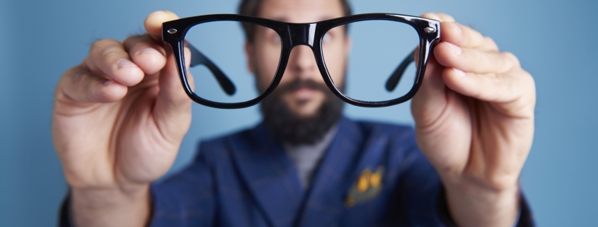 Man holding eyeglasses in front his face