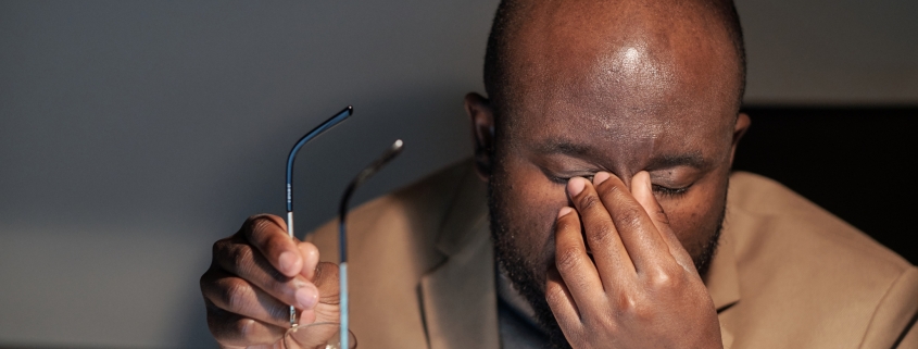 Tired businessman rubbing his eyes during night work