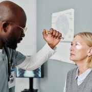 Young confident opthalmologist examining retina of mature female patient